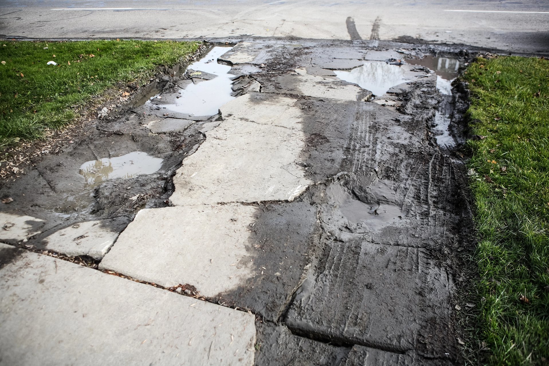 Damaged driveway with uneven and cracked concrete, showing the need for professional repair services.
