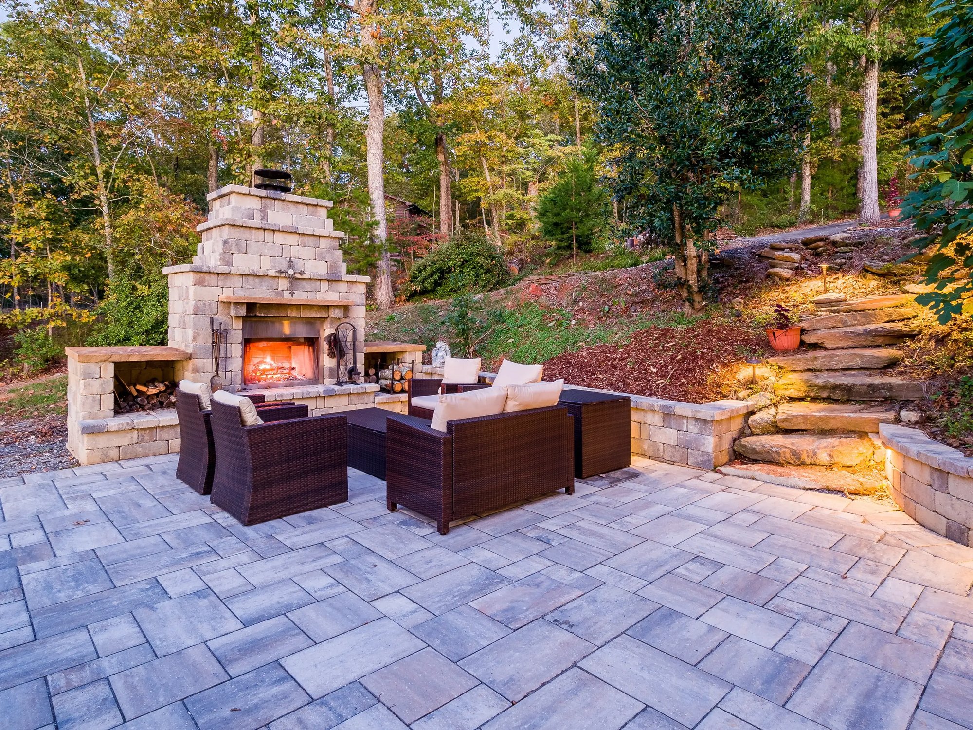 Outdoor patio with a stone fireplace, surrounded by nature and comfortable seating, perfect for evening relaxation