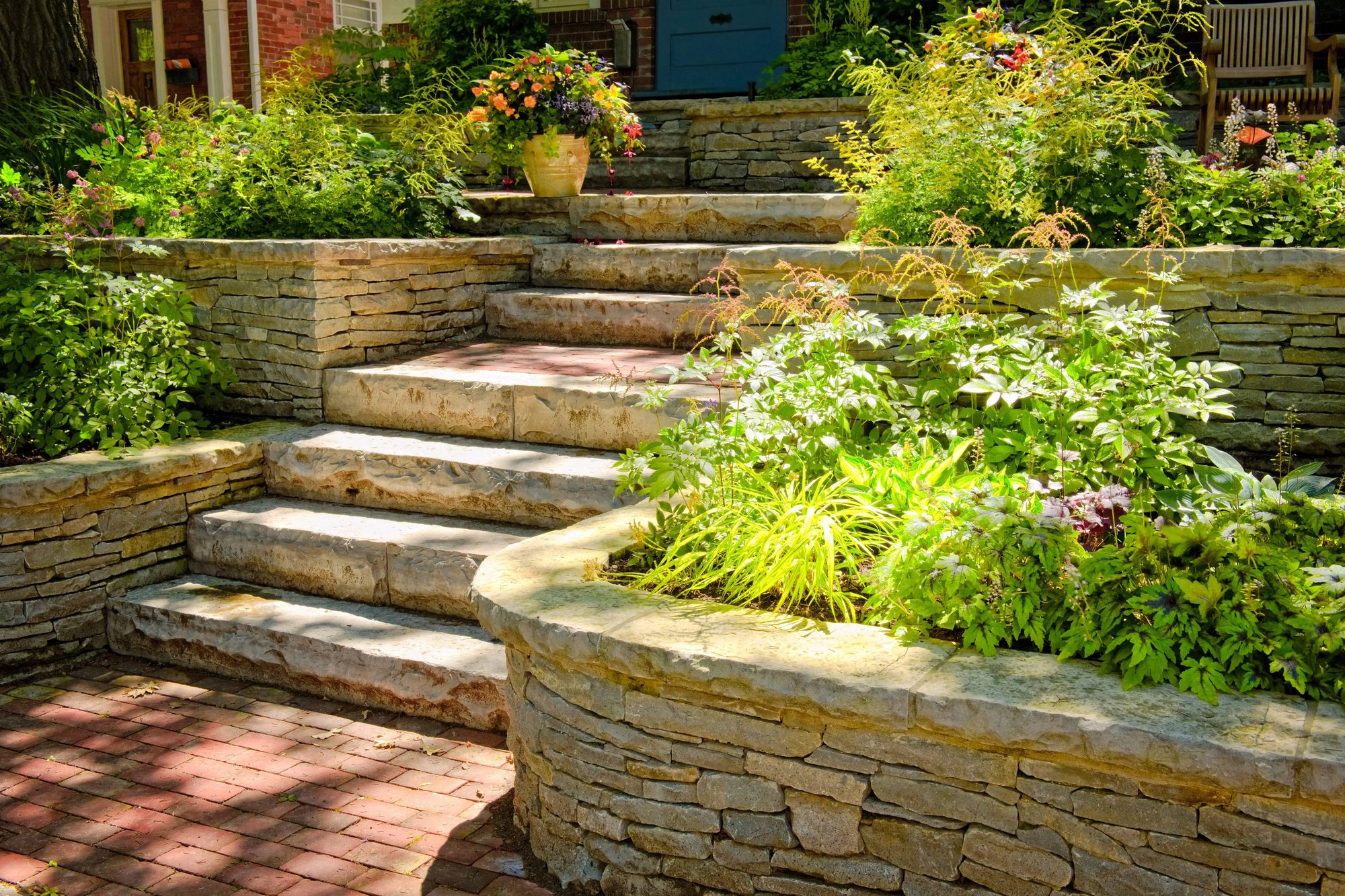 Beautifully designed garden with tiered stone retaining walls and steps, showcasing intricate masonry work that enhances the landscape's natural beauty