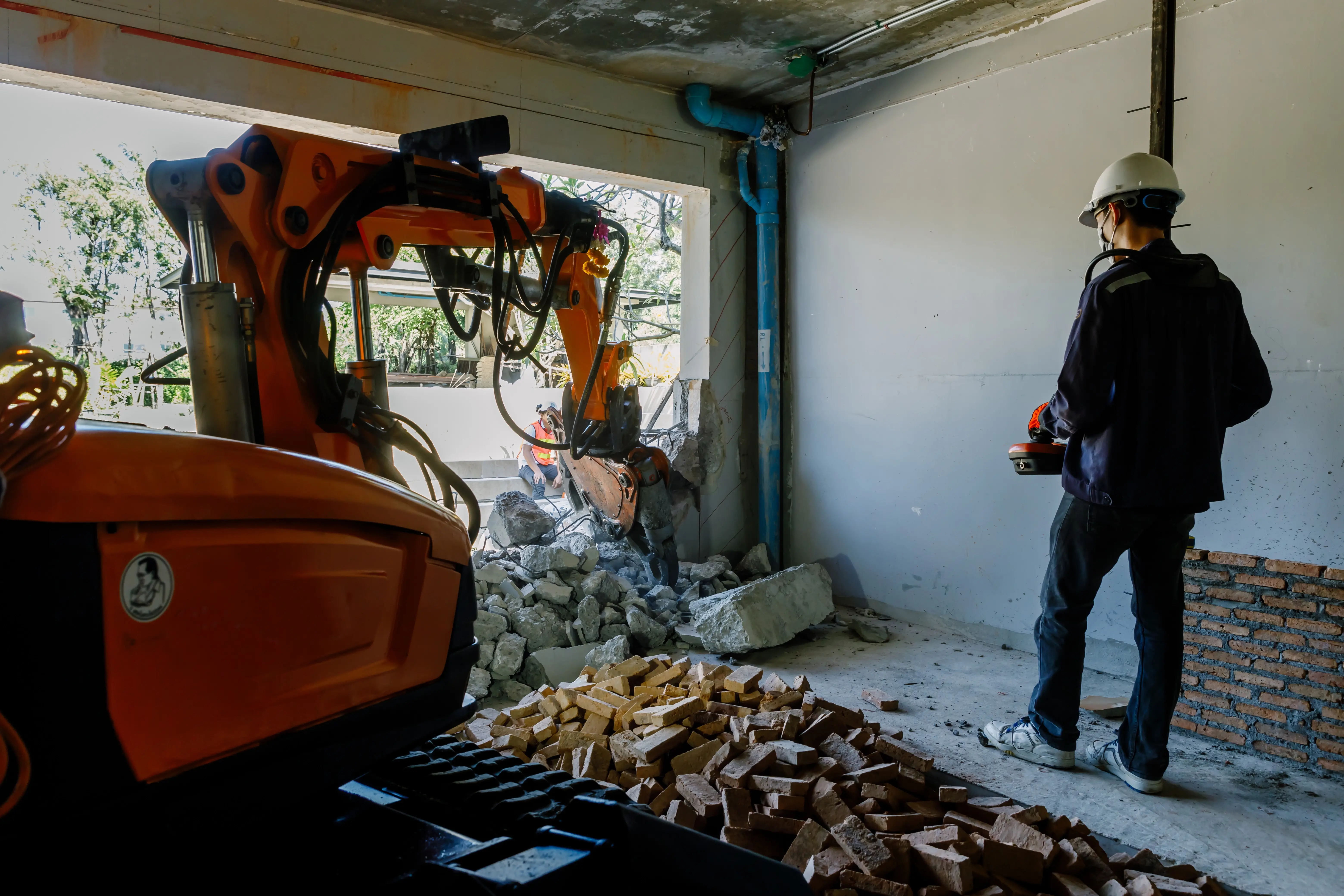 Construction worker operating a hydraulic breaker for concrete excavation inside a building in Philadelphia