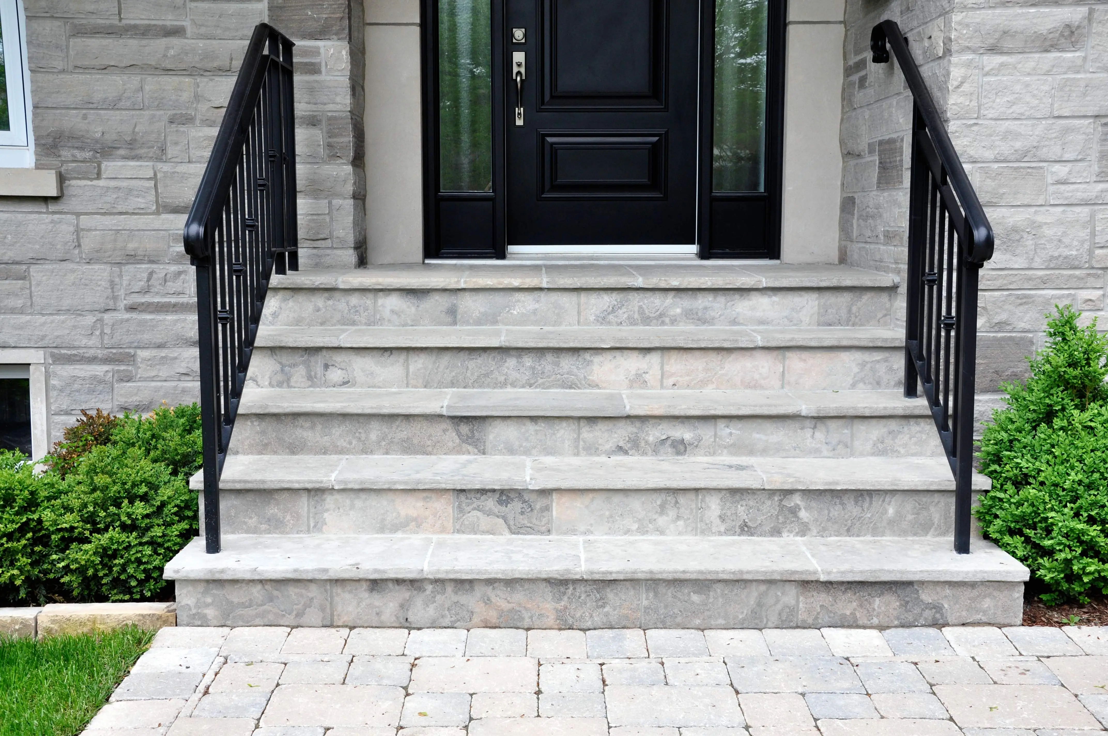 Elegant stone front steps with black metal railings crafted by Main Line Masonry Contractors, demonstrating quality workmanship and attention to detail