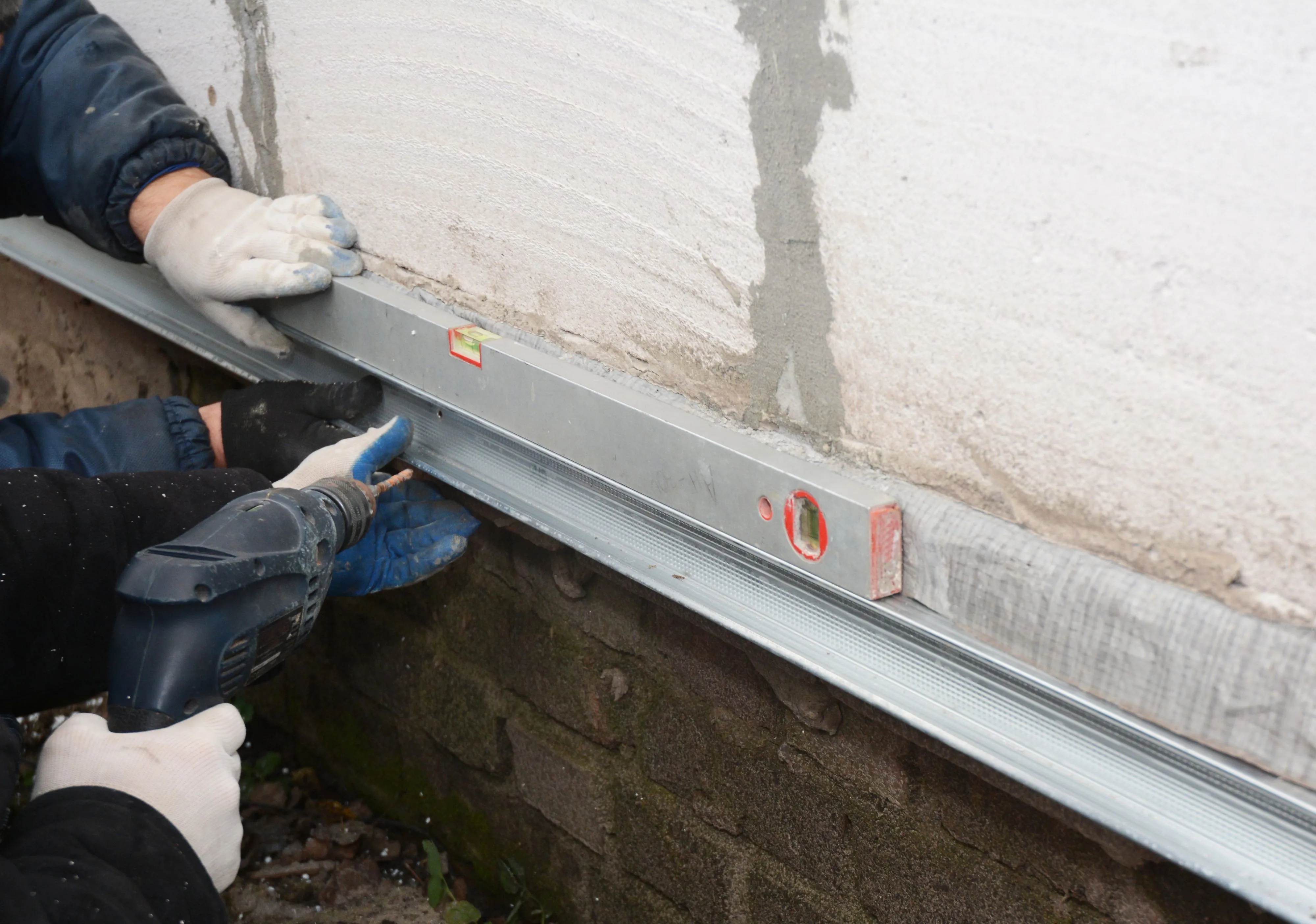 Workers installing a waterproofing system on a basement wall in Philadelphia